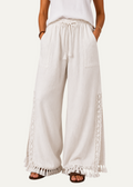 Zeemara white wide-leg pull-on pants featuring side crochet panels, deep pockets, and a fringed tassel hem.